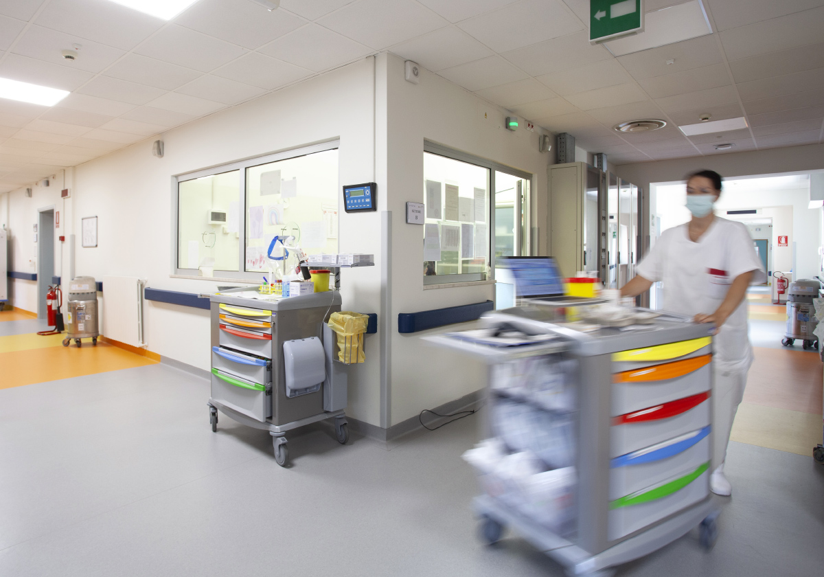 Nurse with trolley moving in adult hospital ward